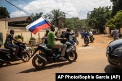 Сторонники одной из противоборствующих сил размахивают российским флагом на улицах Уагадугу, Буркина-Фасо, 2 октября 2022 года. В этой стране присутствует подразделение «ЧВК Вагнер»