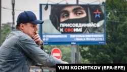 Čovek ispred plakata koji promoviše vojnu obavezu i prikazuje ruskog vojnika i slogan "Pridruži se svojima", Moskva, 25. maja 2023.
