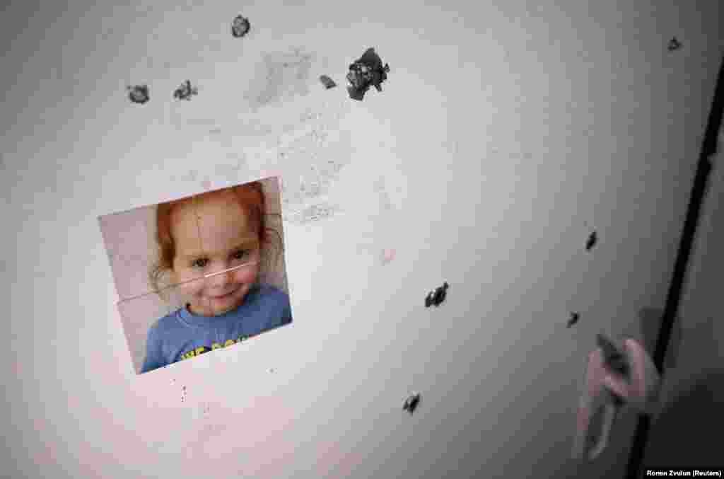 На двери обстрелянного дома приклеена фотография девочки, похищенной 7 октября боевиками радикальной группировки ХАМАС (признанной США и ЕС террористической организацией) из израильского поселения Нир-Оз. 21 ноября, 2023. (REUTERS/Ronen Zvulun )