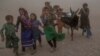 Afghan girls and women carry donated aid to their tents during a fierce sandstorm after the earthquake in Zendah Jan district in Herat Province in October 2023.
