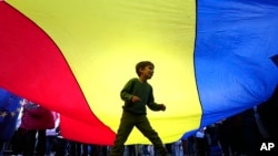 A boy plays underneath a giant national flag during an electoral rally supporting presidential candidate Nicusor Dan in Bucharest on May 11.