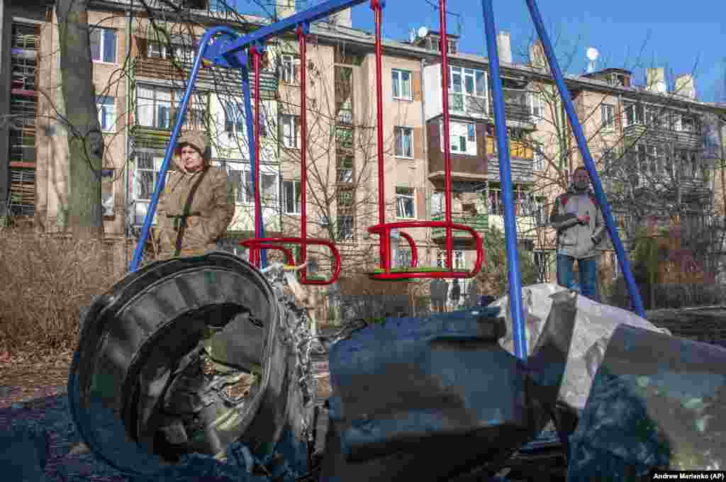 Пас аз ҳамлаи ҳавоии Русия дар Харков, як мард ва як зан дар паҳлӯи таҷҳизоти низомӣ истодаанд. 