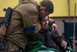 Ukrán katona egy Irpinyből kimenekített asszonnyal 2022. március 30-án