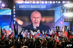 Президент России Владимир Путин на экране, установленном на Красной площади, выступает на митинге и концерте, посвященных «аннексии четырех регионов Украины», сентябрь 2022 года