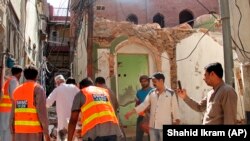 Pakistani volunteers collect debris from a demolished Ahmadi mosque that was demolished by an angry mob on May 24 in the eastern Pakistani city of Sialkot