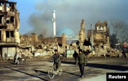 1994. Afgani pe lângă ruinele clădirilor din Kabul, distruse în războiul civil.