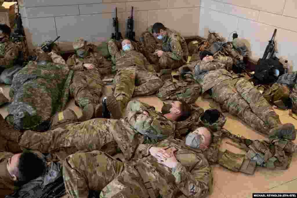 Sute de militari din Garda Națională a SUA se odihnesc în Centrul de vizitatori al Capitoliului, pe Capitol Hill din Washington, DC, SUA, 13 ianuarie 2021. EPA-EFE