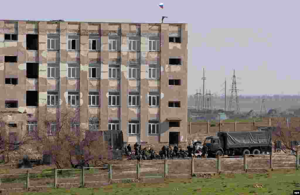 Крымдын Феодосия шаарынын чет жакасындагы украиналык аскер деңиз флотунун базасына карай кетчү жолду орусиялык экендиги жоромолдонгон куралчан жоокерлер тороп турушат. (EPA/ARTUR SHVARTS).