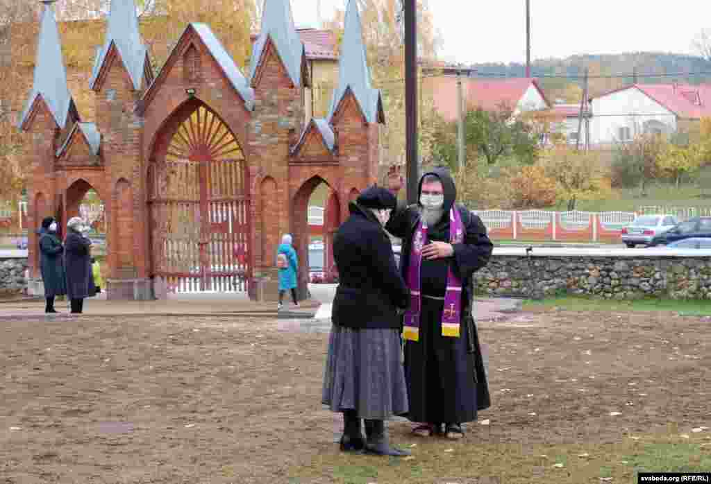 Un preot catolic binecuvântează o femeie într-un cimitir din Ivianiec, Belarus.