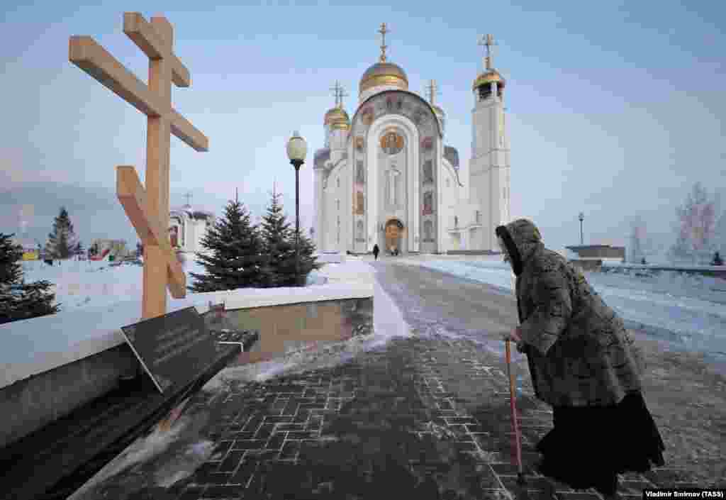 Жанчына моліцца каля мэмарыяльнага крыжа, усталяванага ў памяць ахвяраў выбуху 31 сьнежня 2018 году ў 10-павярховым шматкватэрным доме ў Магнітагорску. Тады загінулі 39 чалавек. Улады заявілі, што гэта выбух прыроднага газу, але ў нядаўняй справаздачы расейскіх дасьледчых журналістаў сьцьвярджаецца, што выбух быў актам тэрарызму.