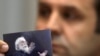 Rasim Ljajić, predsednik Nacionalnog saveta za saradnju sa Haškim tribunalom, drži fotografiju na kojoj je Radovan Karadžić