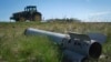 Dio ruske rakete na zemlji dok poljoprivrednik obrađuje svoje polje u ratom razorenoj Harkivskoj oblasti, Ukrajina, april 2024.