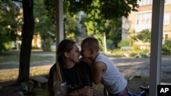 Valeria Potocka házuk előtt ölelgeti ötéves fiát, Dávidot az ukrajnai Kupjanszk-Vuzlovijban 2023. augusztus 23-án