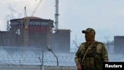 Vojnik sa ruskom zastavom na uniformi ispred nuklearne elektrane Zaporožje