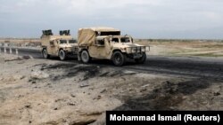 An Afghan military convoy drives past the site of a car bombing where U.S soldiers were killed near Bagram air base on April 9.