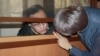 Гражданский активист Махамбет Абжан, которому предъявлено обвинение в мошенничестве, разговаривает со своим адвокатом через проем в огороженном для подсудимых помещении в зале суда. Астана, 16 октября 2017 года. 