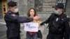 Police officers detain a journalist who holds a placard reading "You Are Afraid Of The Truth" during a single-picket protest against the "foreign agent" law in Moscow in August 2021.