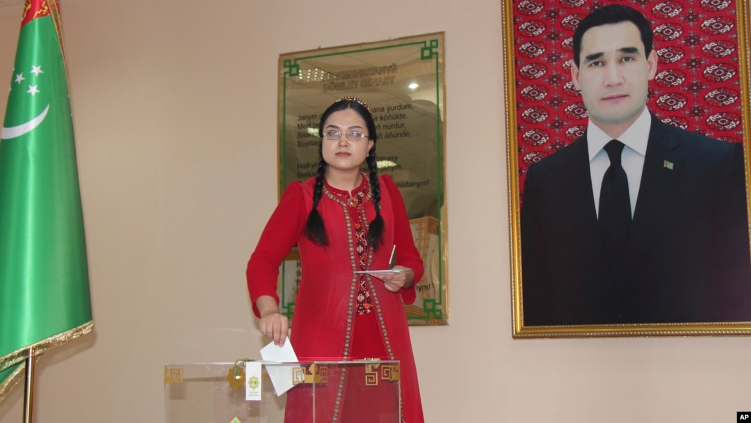 A woman casts her ballot at a polling station in Ashgabat on March 26 featuring a portrait of President Serdar Berdymukhammedov.