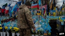 Un soldat lasă două țigări lângă o fotografie cu tovarășul său căzut în Piața Independenței din Kiev, pe 3 februarie.