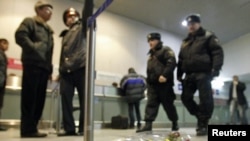 Policajci hodaju pored cvijeća ostavljenog na podu u znak sejćanja na one koji su ubijeni u eksploziji na aerodromu Domodedovo u Moskvi, 25. januar 2011.