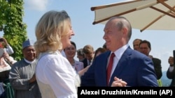 Австрия тышкы иштер министри Карин Кнайсль жана Орусия президенти Владимир Путин министрдин тоюнда бийлеп жатышат.
