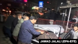 Afghan health workers carry an injured man to the hospital after a car bomb targeted a foreigners' compound in Kabul on January 14.
