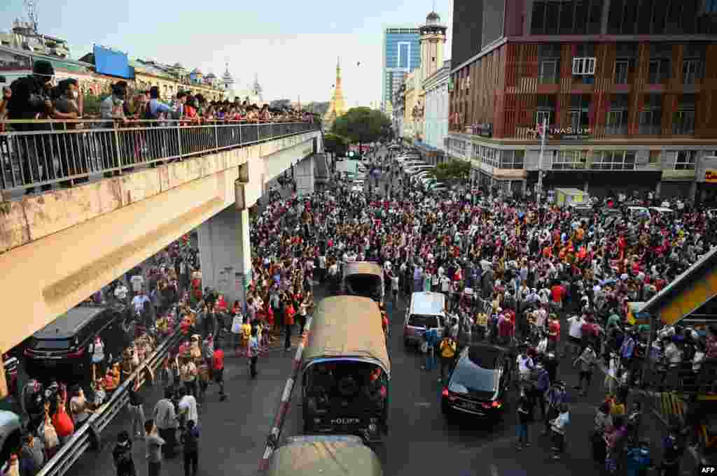 Disa kamionë duke transportuar policë kalojnë mes protestuesve të cilët mbajnë një demonstratë kundër grushtit të shtetit ushtarak në Yangon, 6 shkurt, 2021. (YE AUNG THU/AFP)