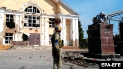 Украінскі вайсковец на цэнтральнай плошчы захопленай Суджы са зьнішчаным помнікам савецкаму дыктатару Леніну