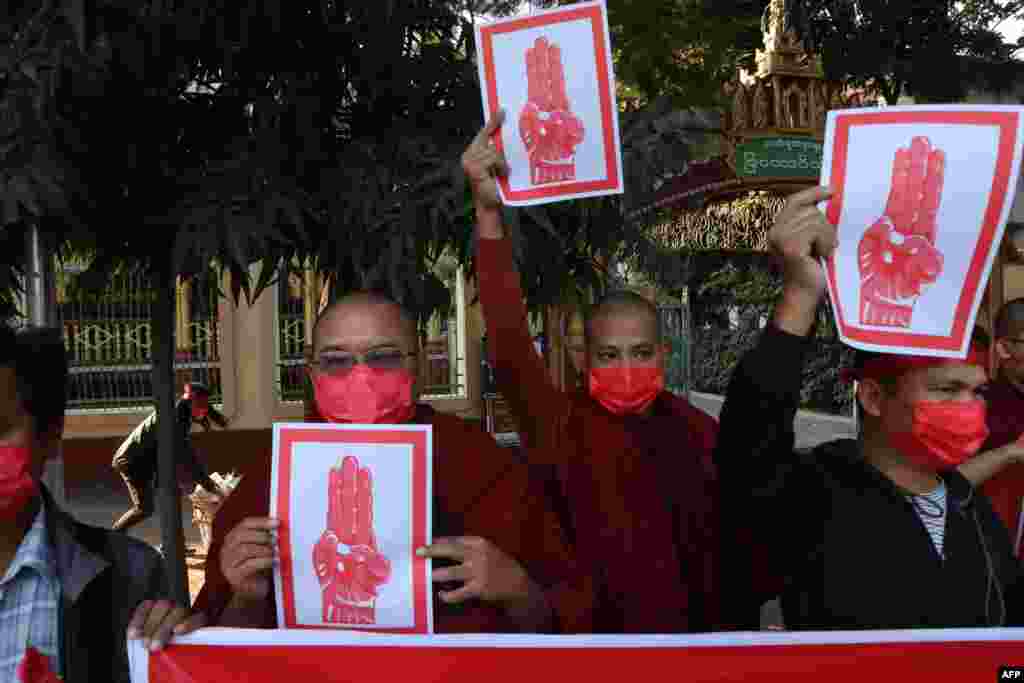 Disa murgj budistë mbajnë shenja që tregojnë përshëndetjen me tre gishta gjatë një demonstrate kundër puçit ushtarak në Mandalay, 8 shkurt, 2021. (Foto nga STR/AFP)